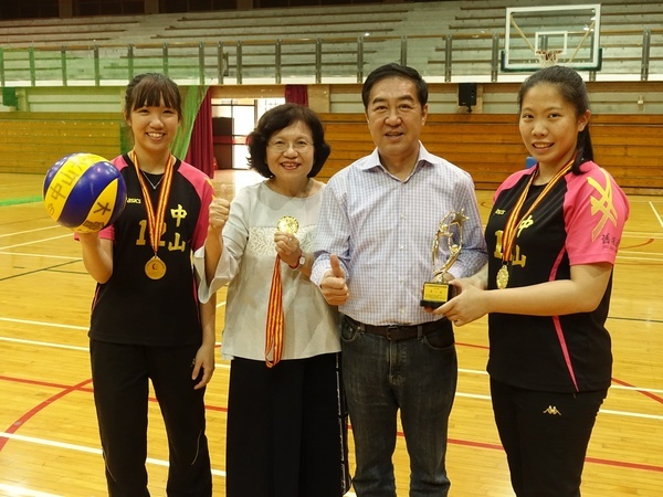 中山大學女排成員楊子琳(左一)與簡鸝樺(右一)參加兩岸四地比賽摘金，獻獎給副校長蔡秀芬(左二)及舊振南食品公司董事長李雄慶(左三)。圖片